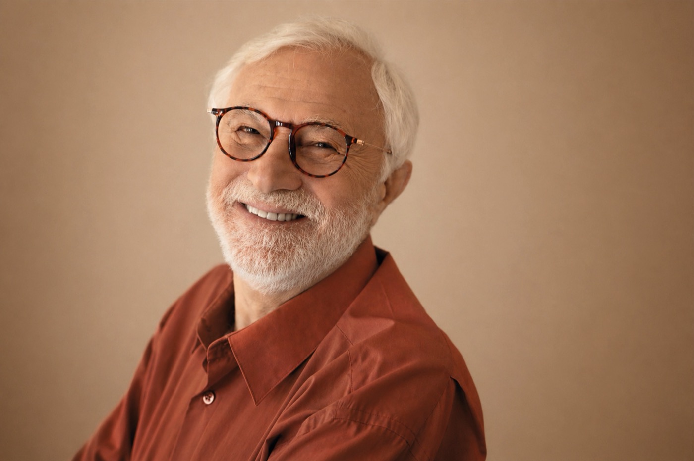 Un uomo con occhiali, in camicia color terracotta, nella luce calda di una finestra